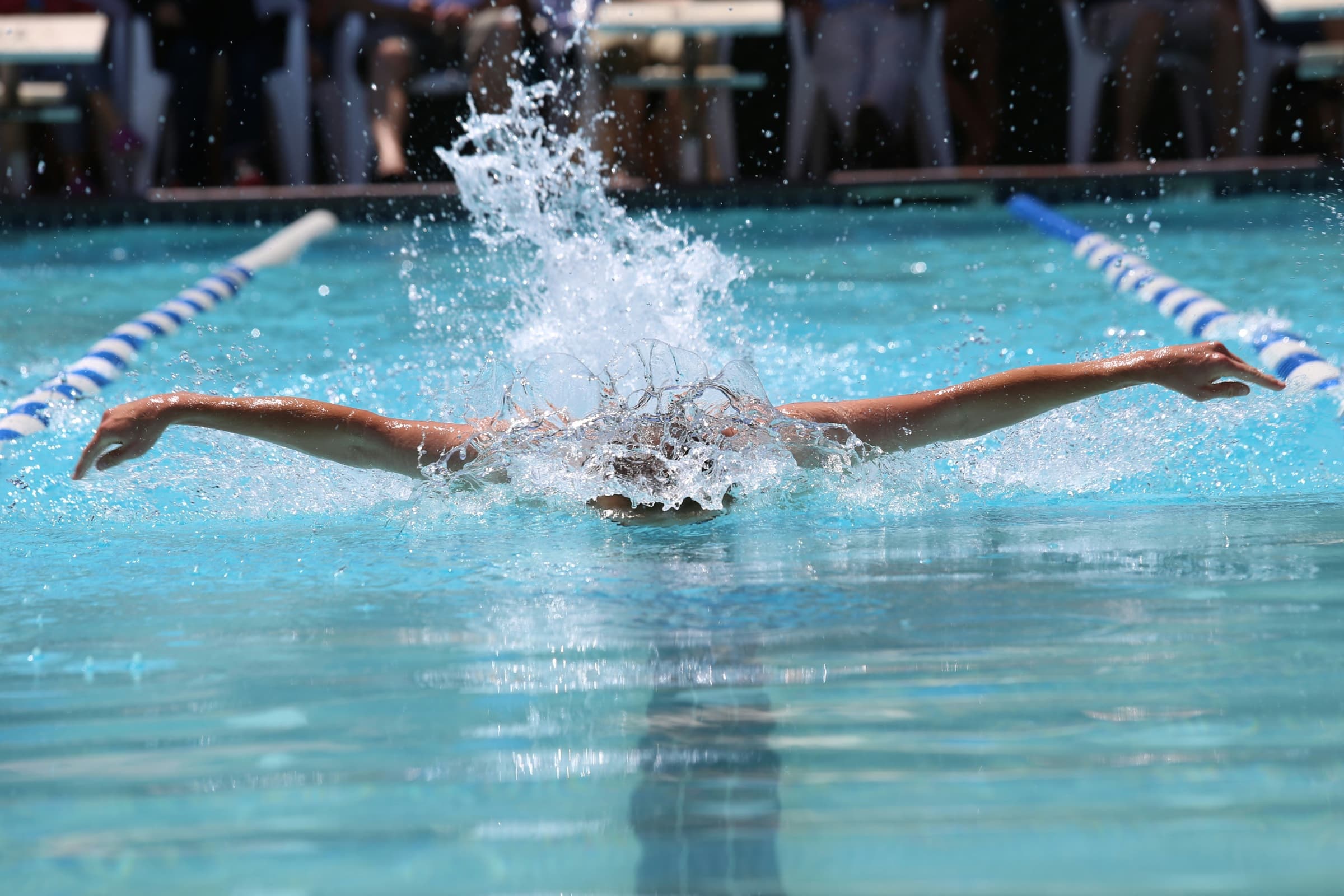 Competitive swimmer racing butterfly in an outdoor pool