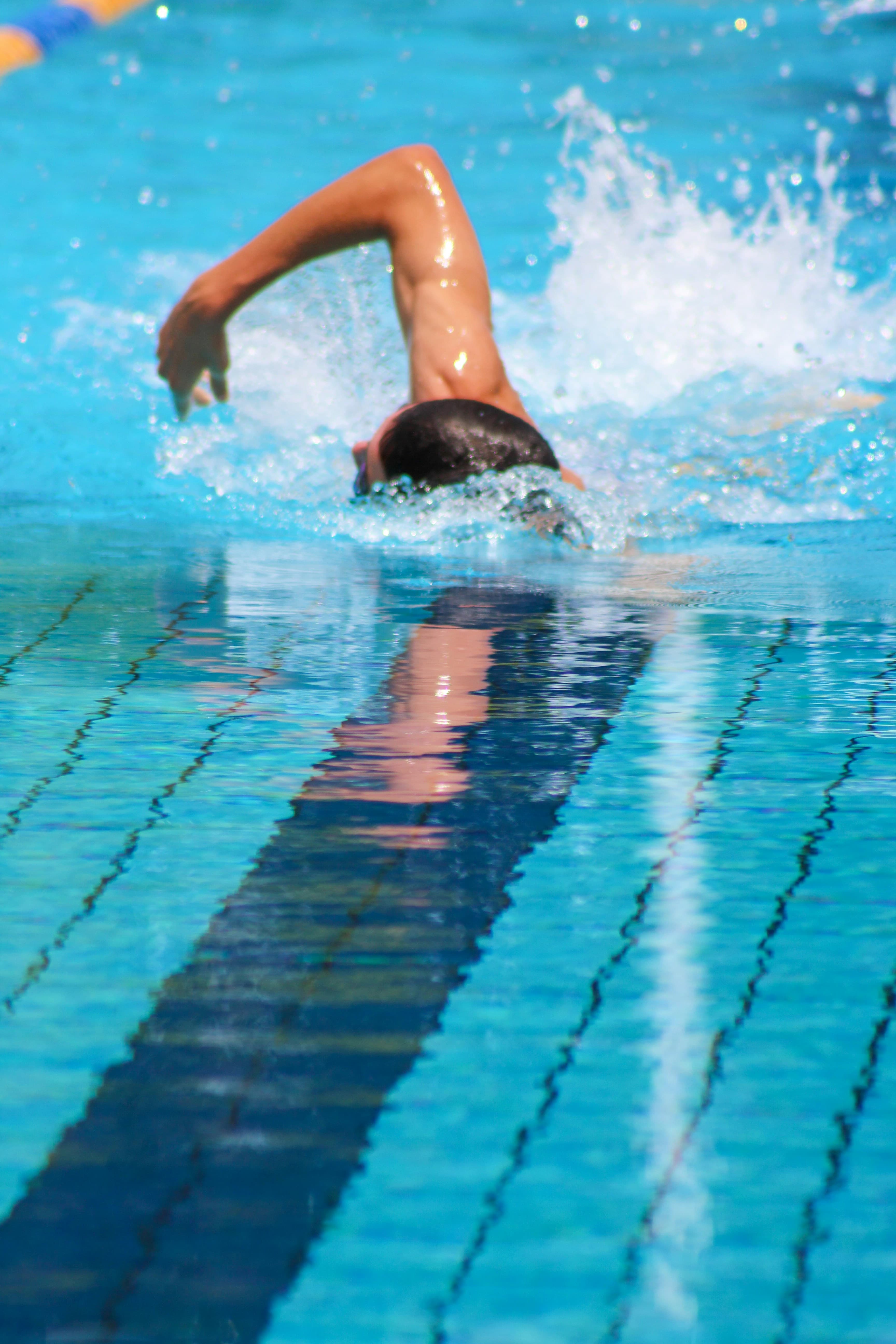 A swimmer swimming freestyle towards the camera in a blue swimming pool