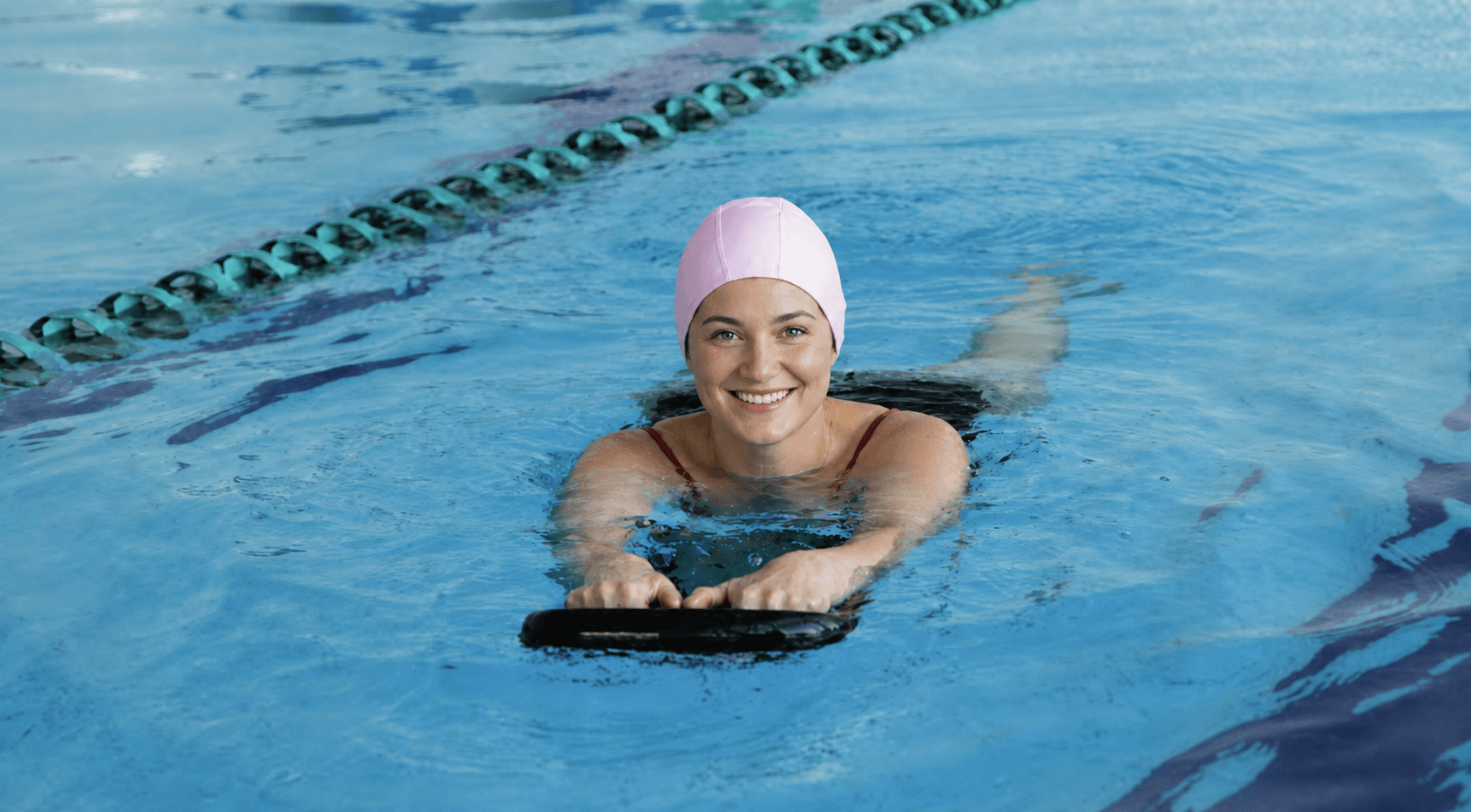Adult swimmer training with a kickboard in the pool