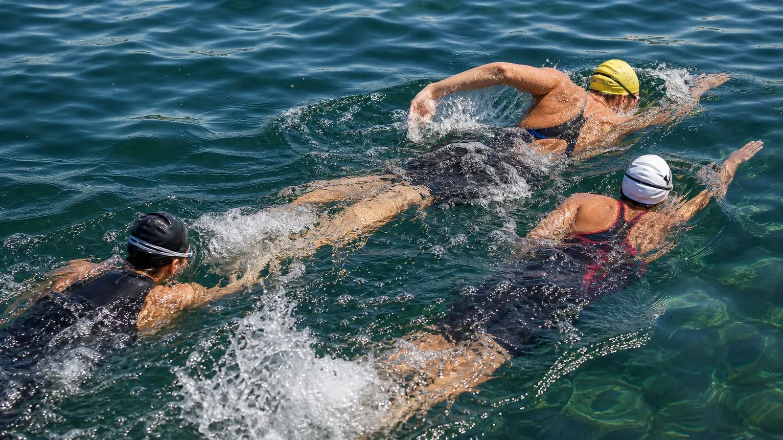 Three competitors drafting closely in an open-water race